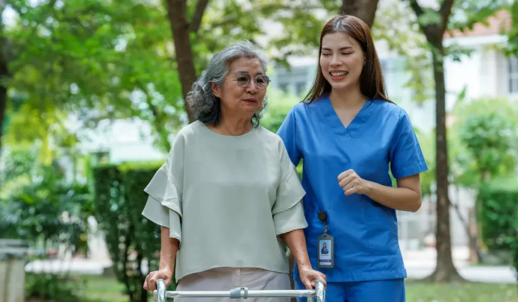 Caregiver provides assistance and support to senior in park, showcasing importance of care and companionship in enhancing quality of life