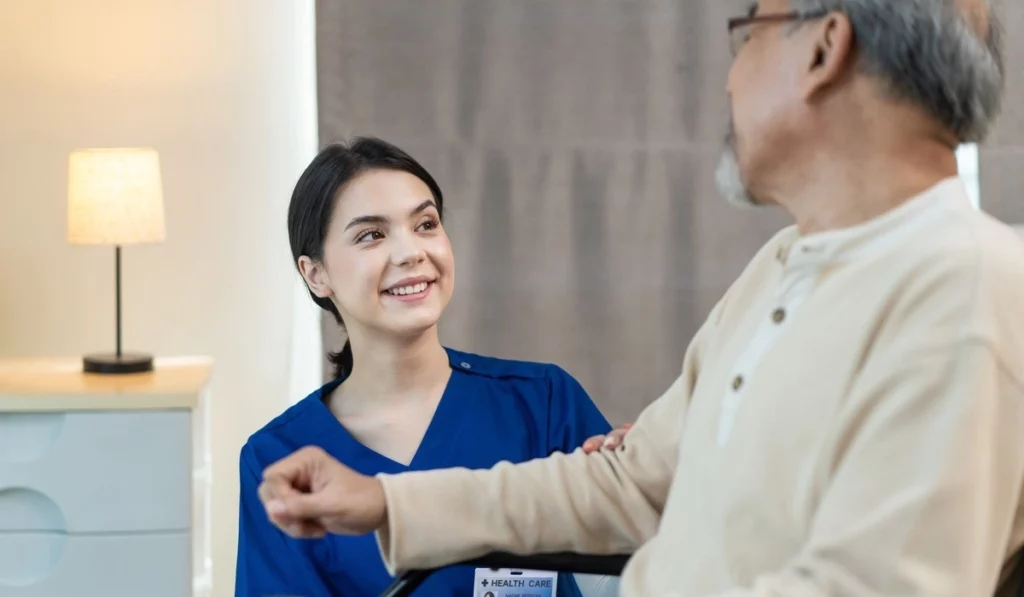 happy Caregiver girl greeting and talking with mature disabled patient
