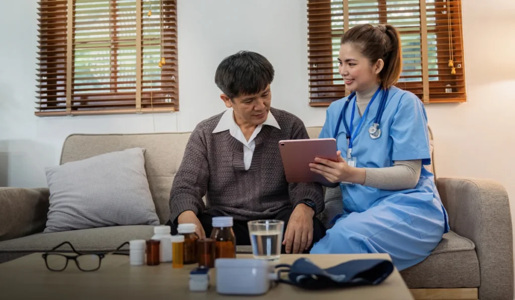 Doctor or caregiver and senior man going through medical record on digital tablet during home visit